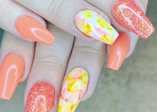 Close-up of vibrant nail art at Nail'd It, Todmorden, England, GB featuring orange and marbled designs.