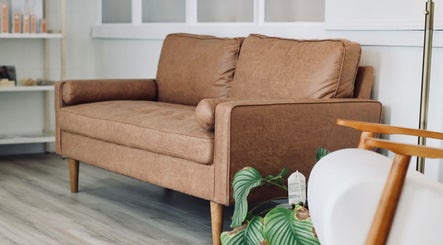Elegant seating area at Cyr Aesthetics, Petawawa, Ontario, CA with a stylish tan sofa and lush plant.