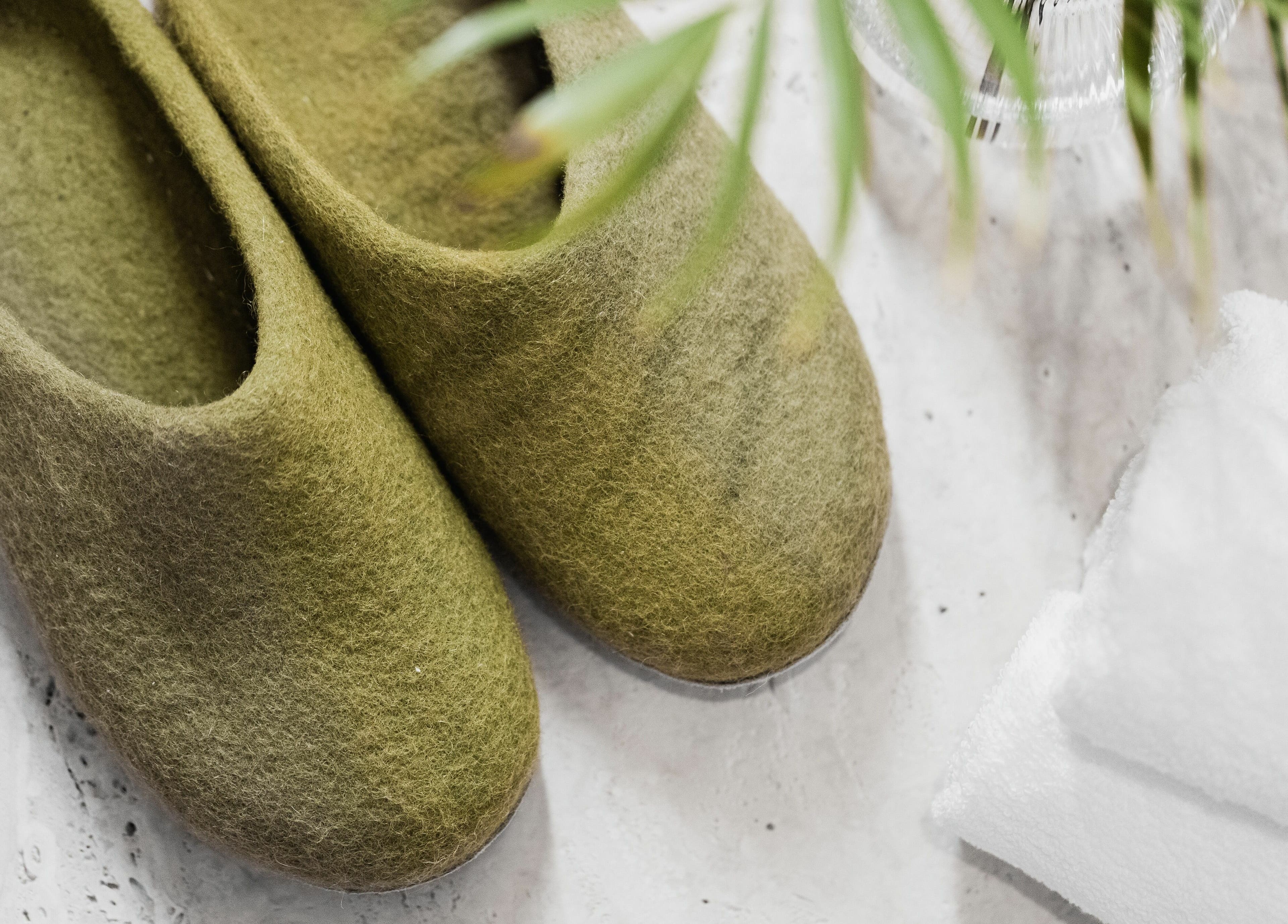 Green felt slippers on a marble floor with white towels at Another Mars, Dubai, Dubai, AE.