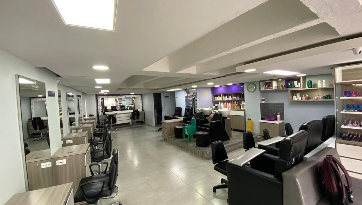 Interior moderno de Lolas Peluqueria en Bogotá, Bogotá, CO con sillas y estantes de productos.