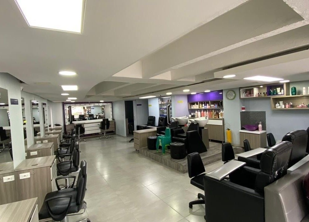 Interior moderno de Lolas Peluqueria en Bogotá, Bogotá, CO con sillas y estantes de productos.