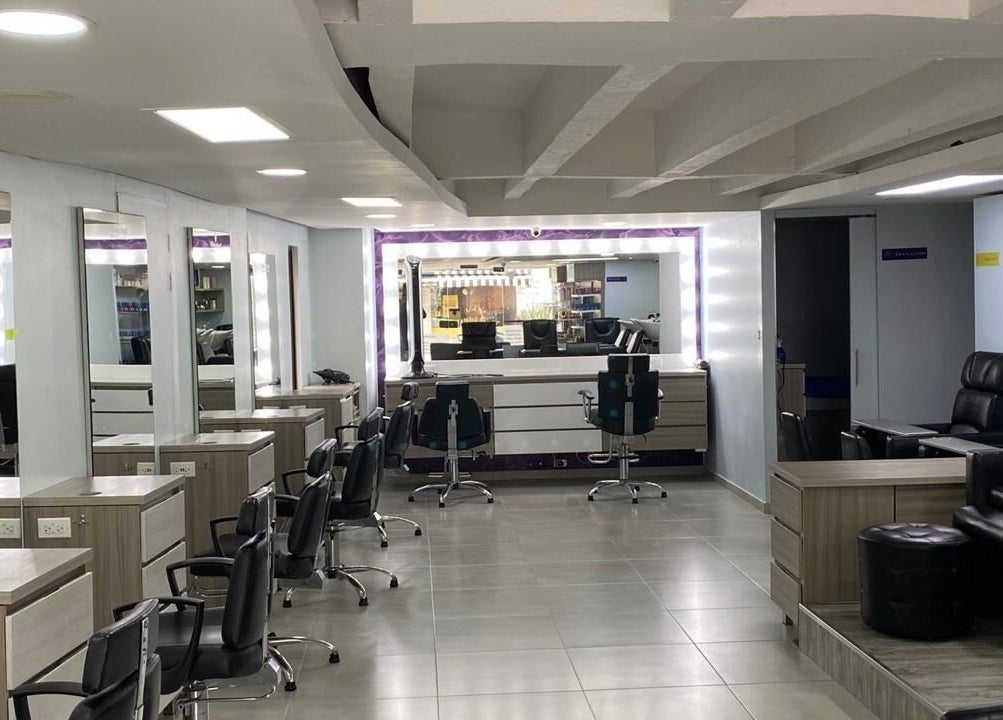 Interior moderno y elegante de Lolas Peluqueria en Bogotá, Bogotá, CO con puestos y espejos iluminados.