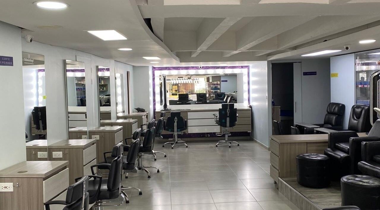 Interior moderno y elegante de Lolas Peluqueria en Bogotá, Bogotá, CO con puestos y espejos iluminados.