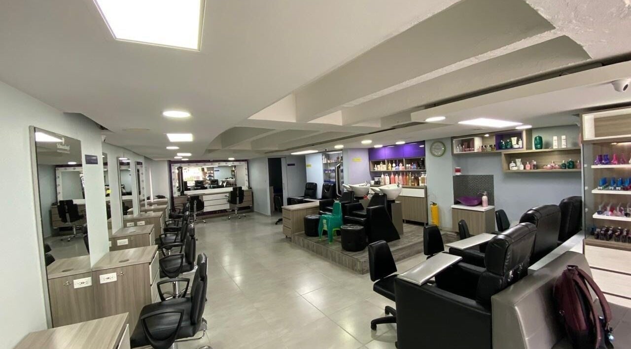Interior moderno de Lolas Peluqueria en Bogotá, Bogotá, CO con sillas y productos de belleza.