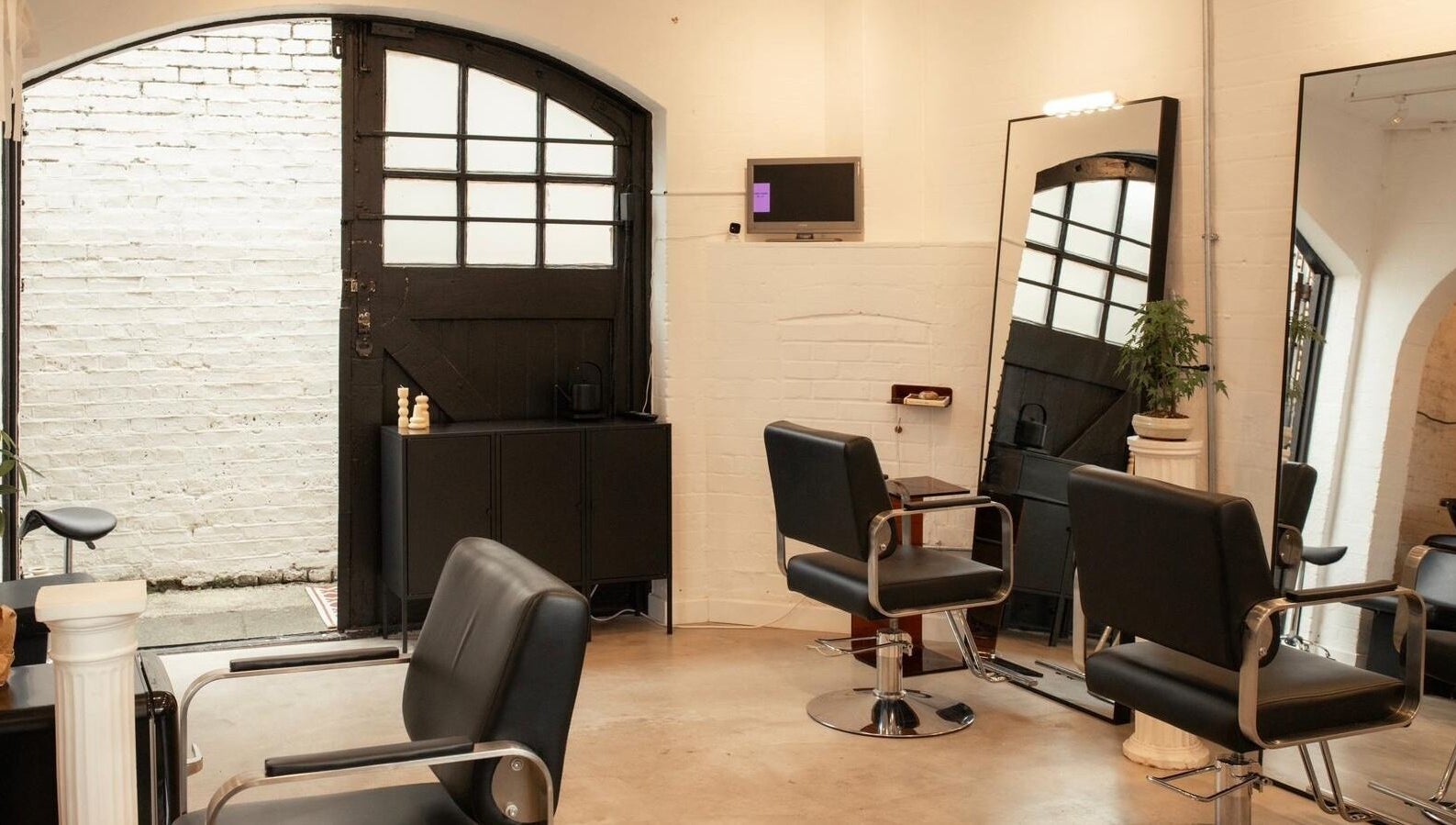 Modern salon interior at Studio Studios, London, England, GB featuring sleek chairs and large mirrors.