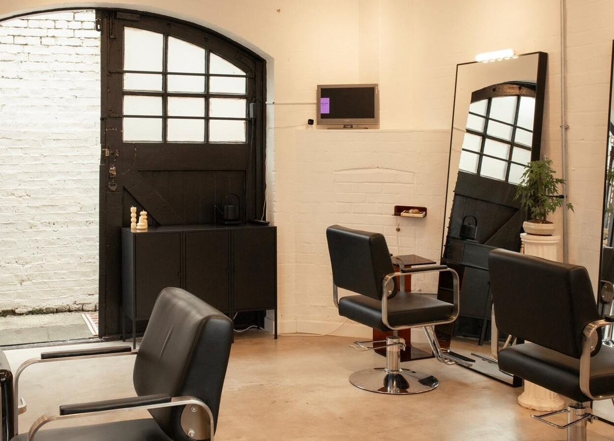 Modern salon interior at Studio Studios, London, England, GB featuring sleek chairs and large mirrors.