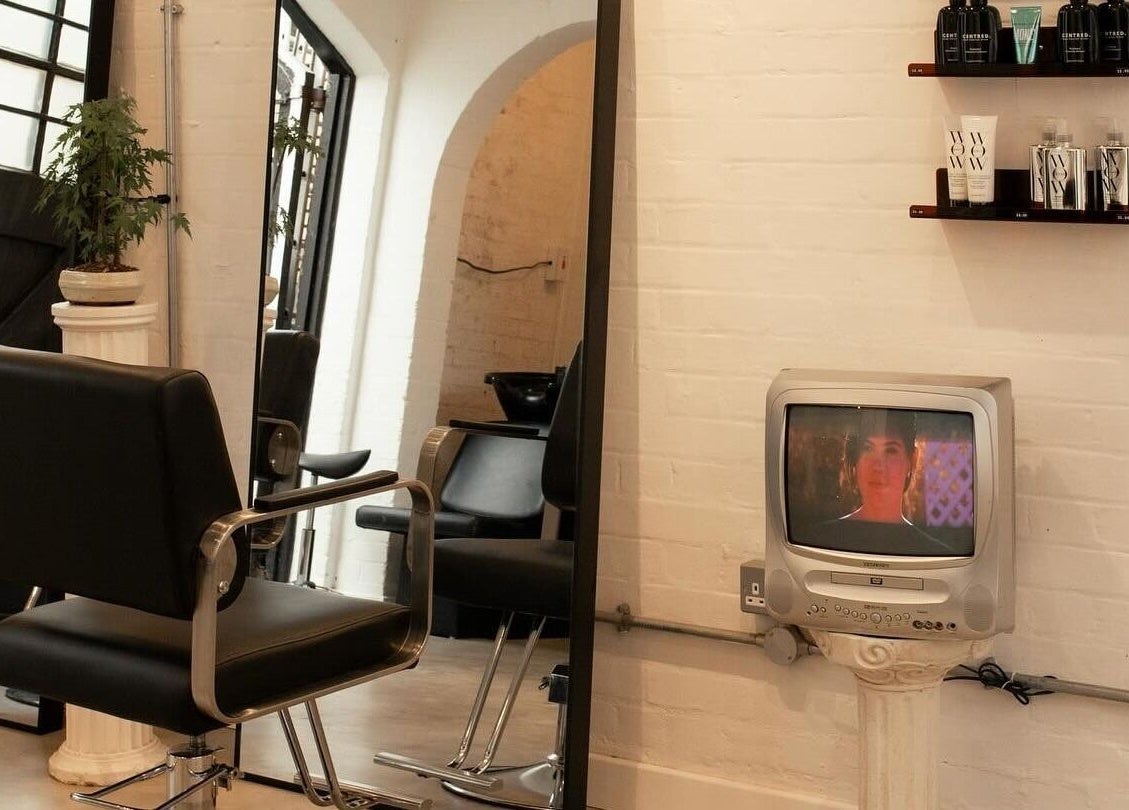Chic hair salon corner at Studio Studios, London, England, GB showcasing modern chairs and retro TV.