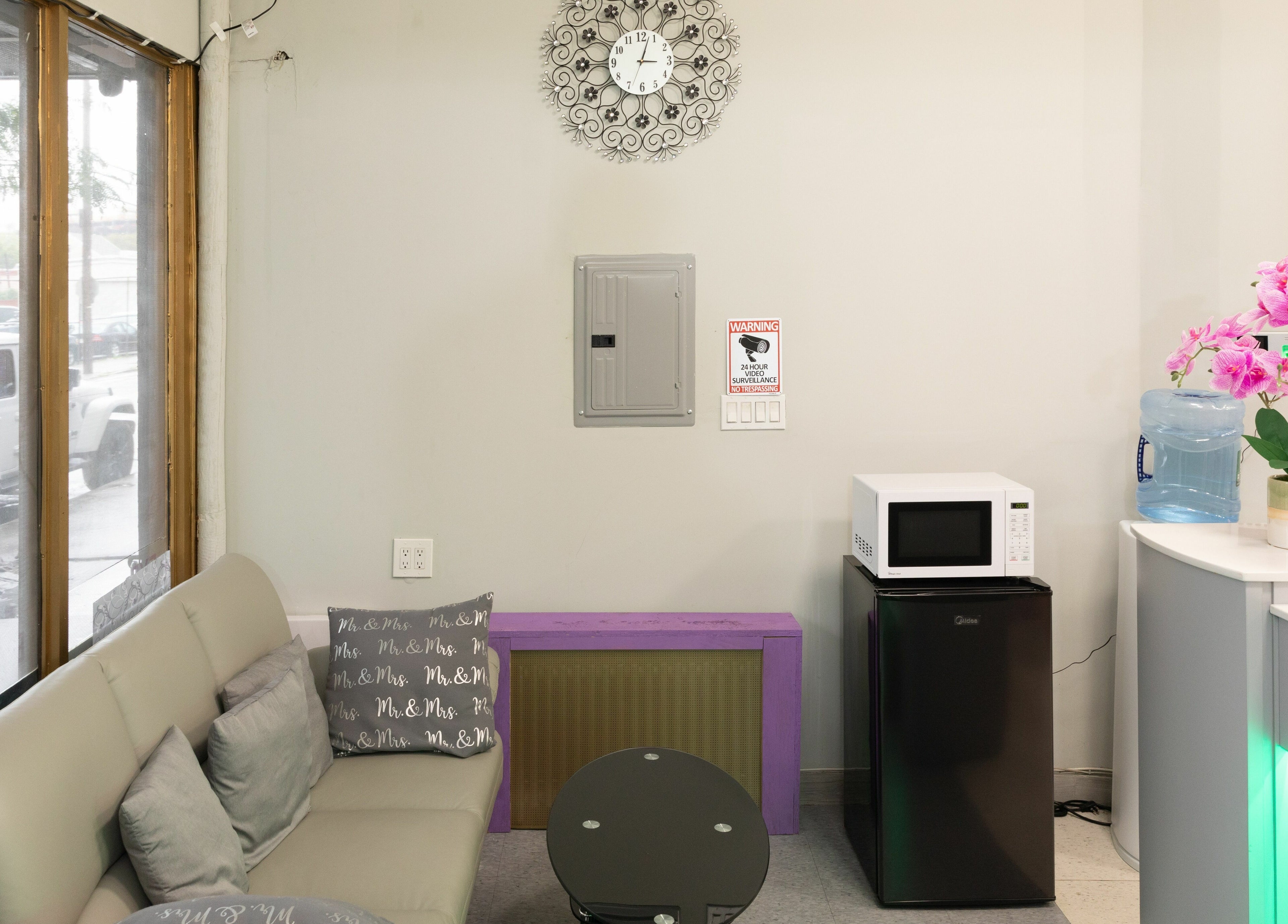 Cozy sitting area at Wonder Lash Studio Queens, Long Island City, US with sofa, pillows, and pink orchids.