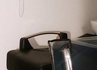 Área de lavado en Rootsxyeliann, Caguas, Caguas, PR. Sillón negro y lavabo moderno en ambiente sereno.