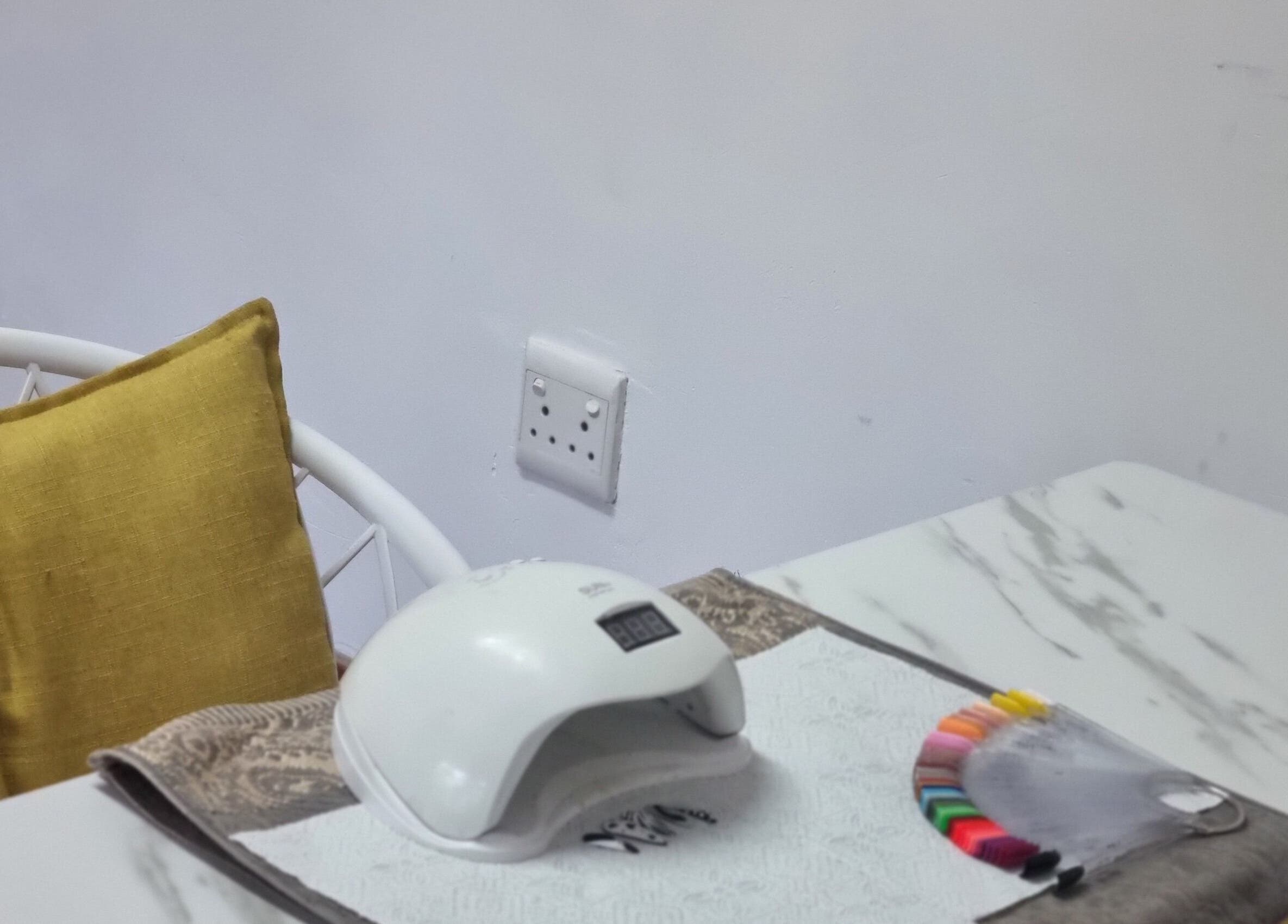 Manicure setup at Enhle Afro Salon, Mthatha, Eastern Cape, ZA featuring a nail dryer and colorful swatches.