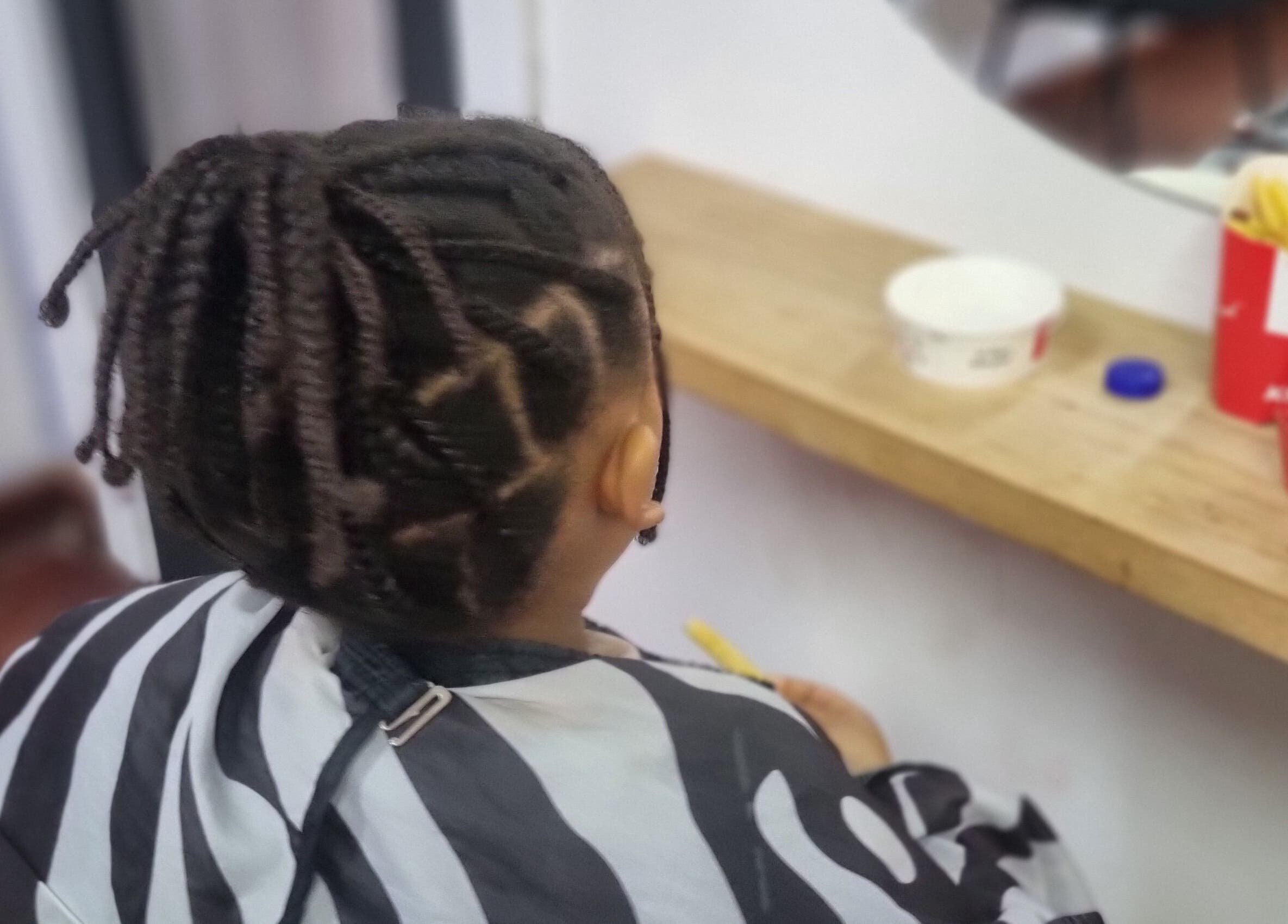 Young child with braided hair at Enhle Afro Salon in Mthatha, Eastern Cape, ZA, reflected in a salon mirror.