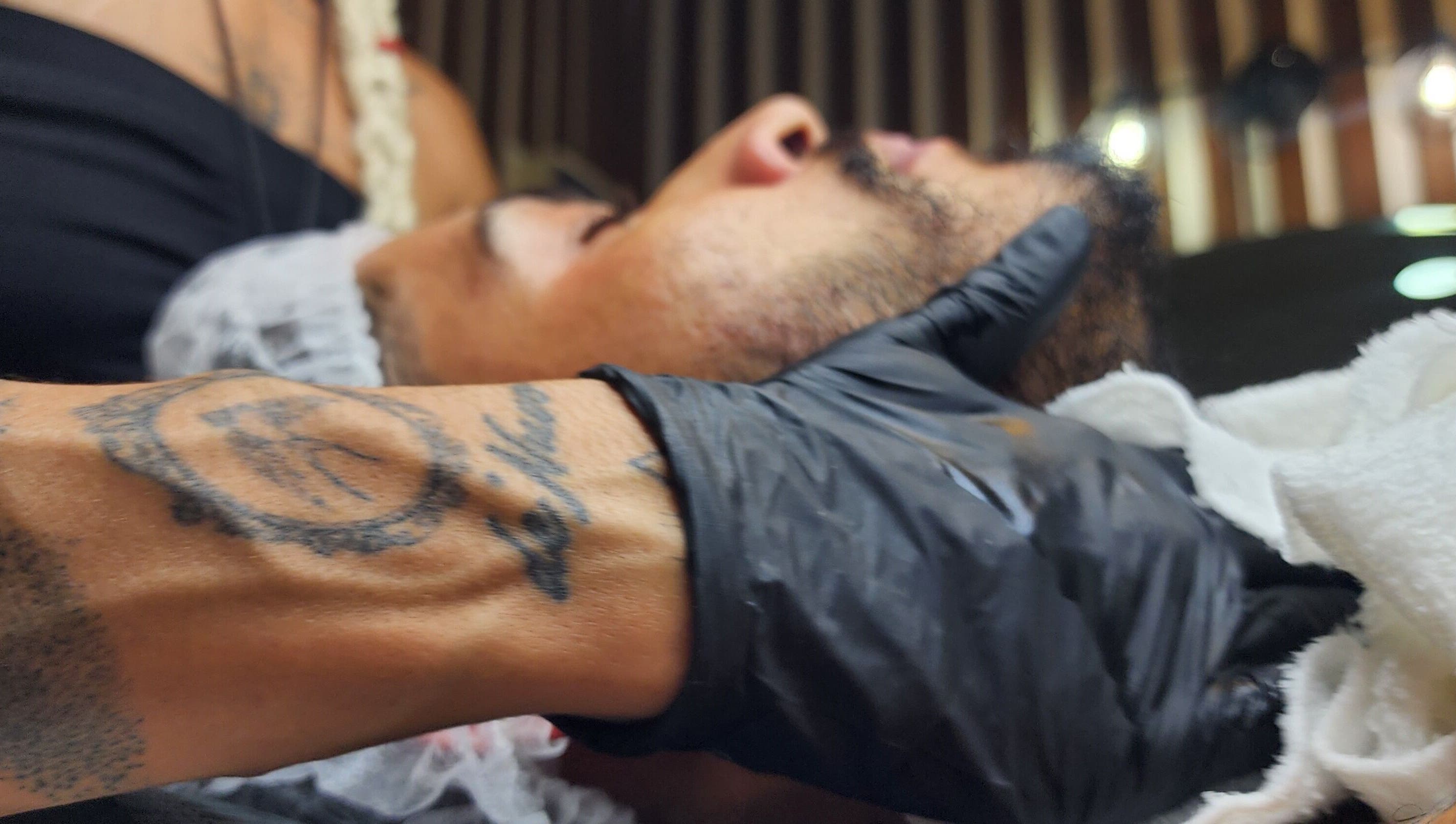 Aura Tattoo session at Sattva Aesthetics, Kralendijk, Bonaire. Gloved artist with tattoo, face in profile.