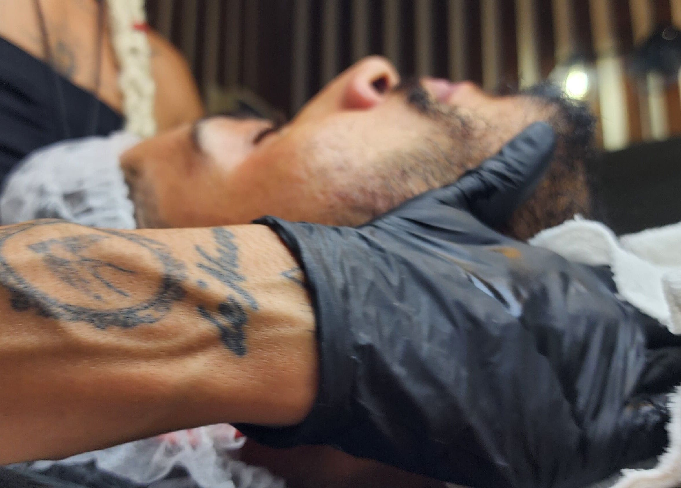 Aura Tattoo session at Sattva Aesthetics, Kralendijk, Bonaire. Gloved artist with tattoo, face in profile.