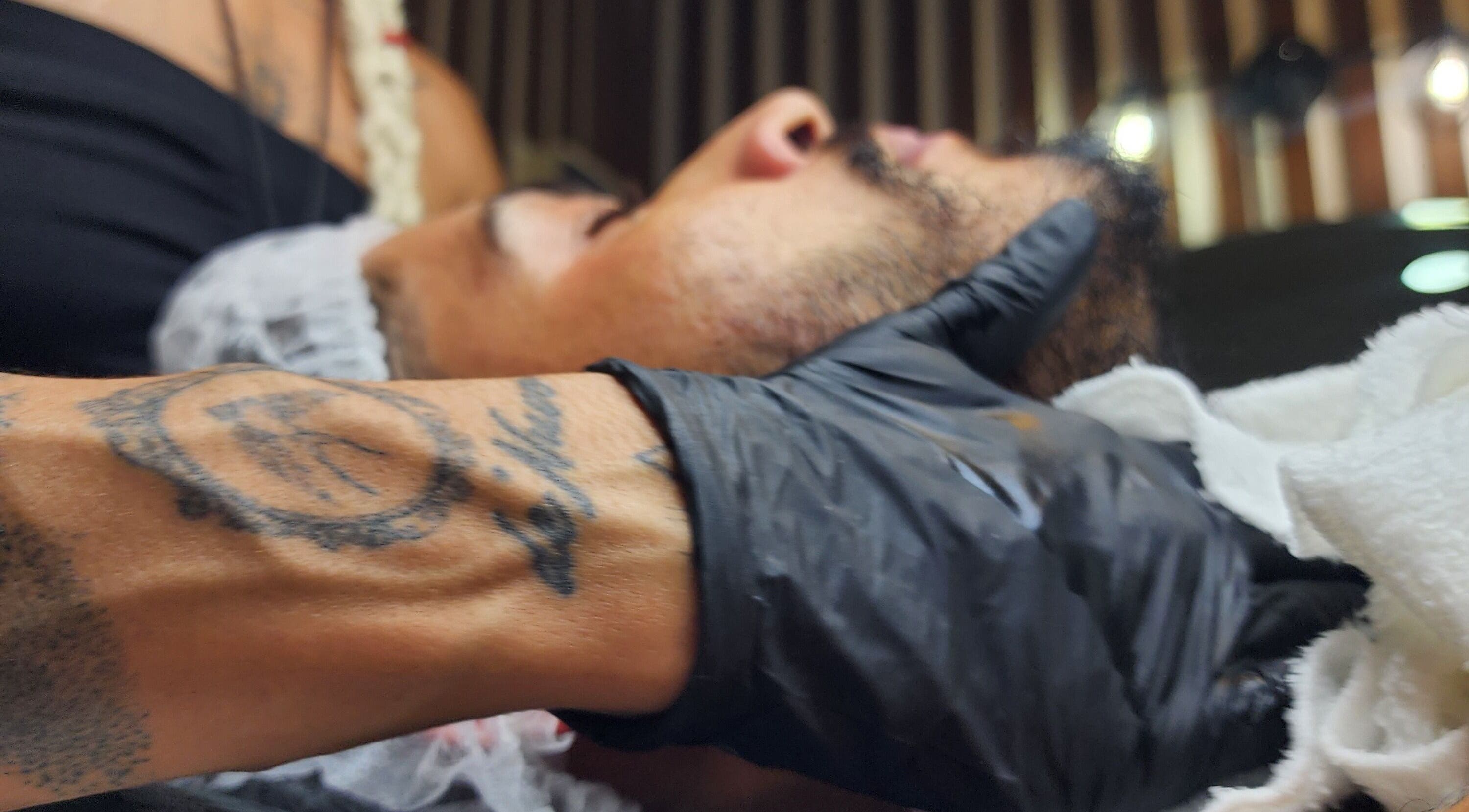 Aura Tattoo session at Sattva Aesthetics, Kralendijk, Bonaire. Gloved artist with tattoo, face in profile.