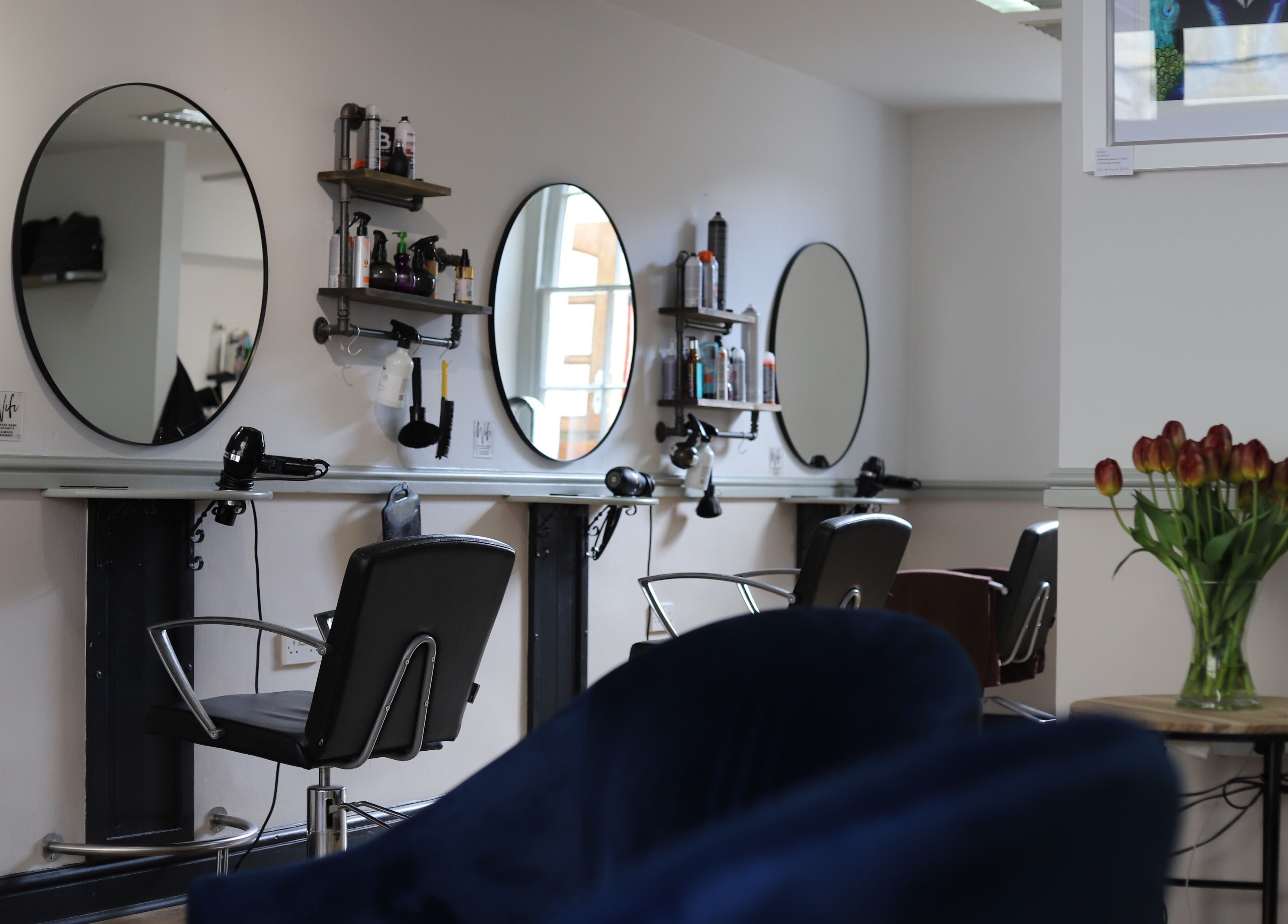 Modern interior of Strawberry Fields Hair Design in Corsham, England, GB with styling stations and tulips.