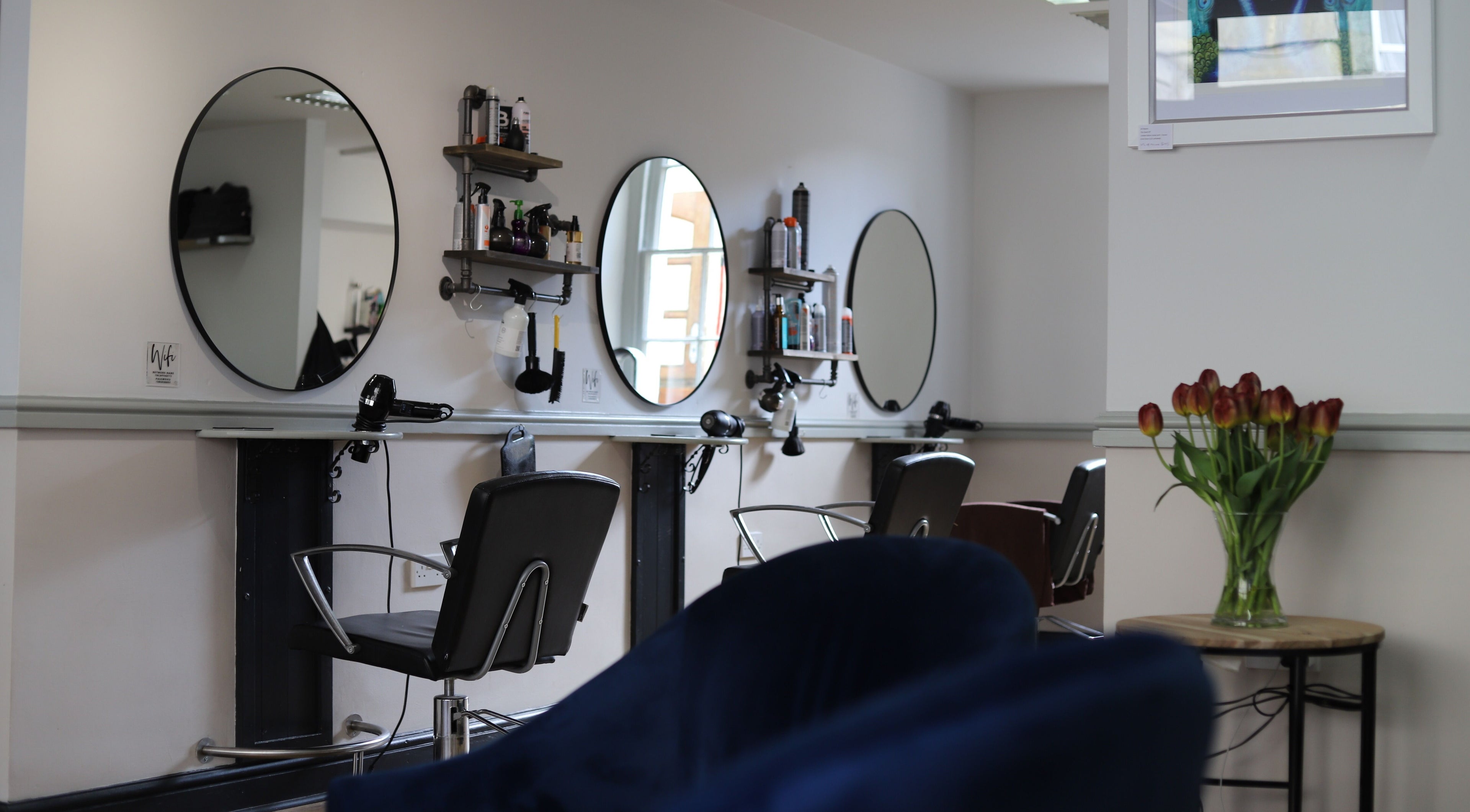 Modern interior of Strawberry Fields Hair Design in Corsham, England, GB with styling stations and tulips.