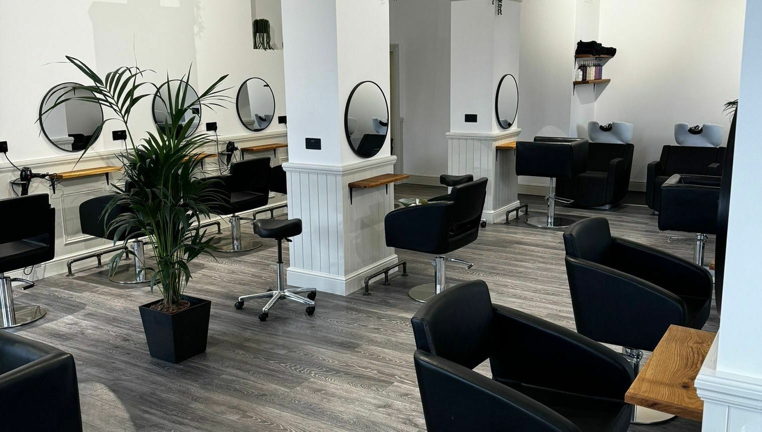 Modern salon interior at David & David, Plymouth, England, GB featuring sleek black chairs and mirrors.