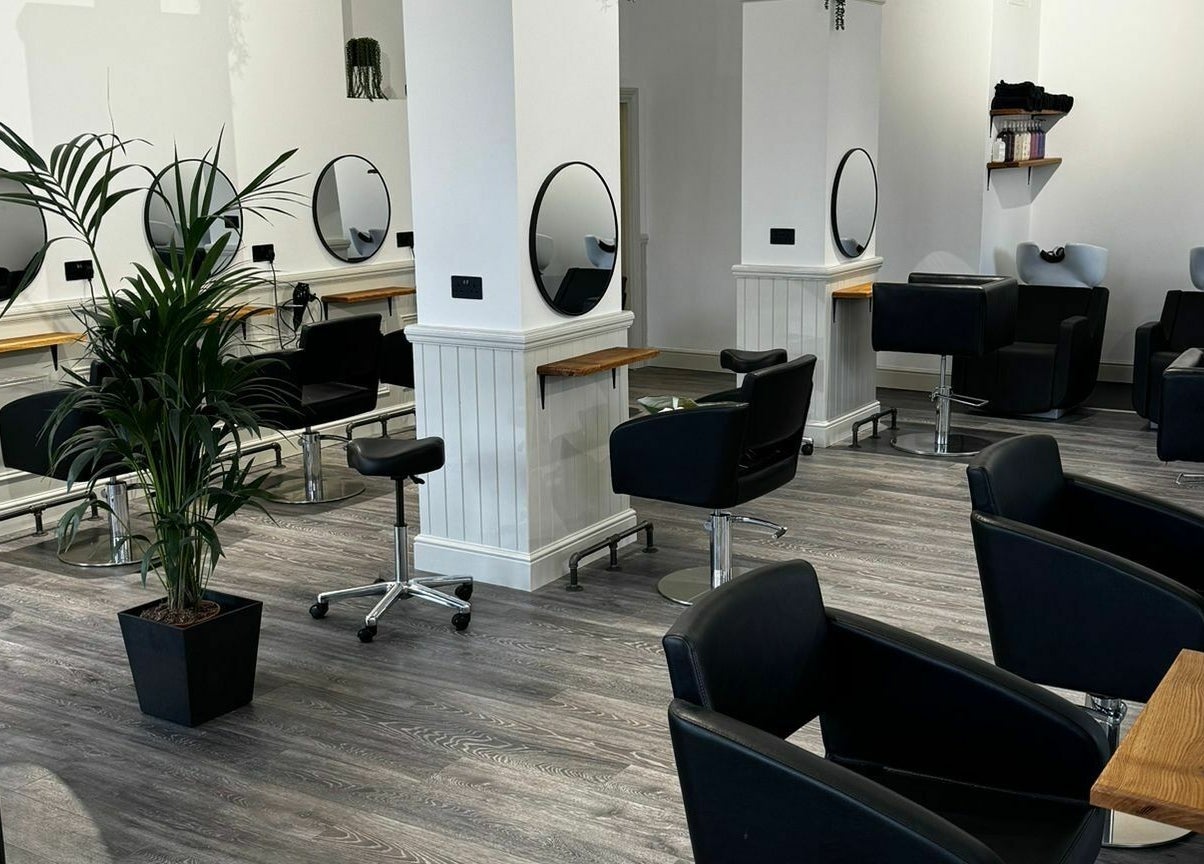 Modern salon interior at David & David, Plymouth, England, GB featuring sleek black chairs and mirrors.