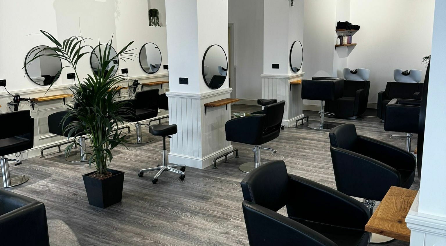Modern salon interior at David & David, Plymouth, England, GB featuring sleek black chairs and mirrors.