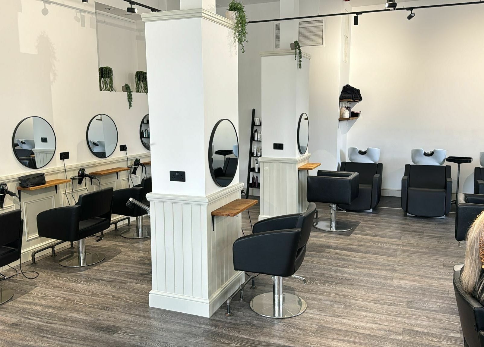 Modern salon interior at David & David in Plymouth, England, GB, featuring sleek black chairs and mirrors.