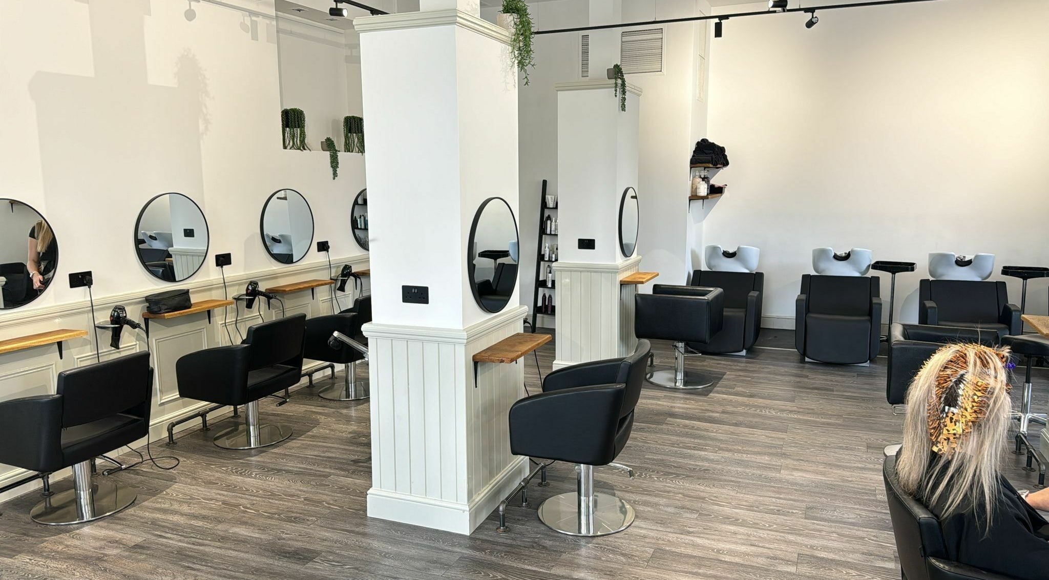 Modern salon interior at David & David in Plymouth, England, GB, featuring sleek black chairs and mirrors.