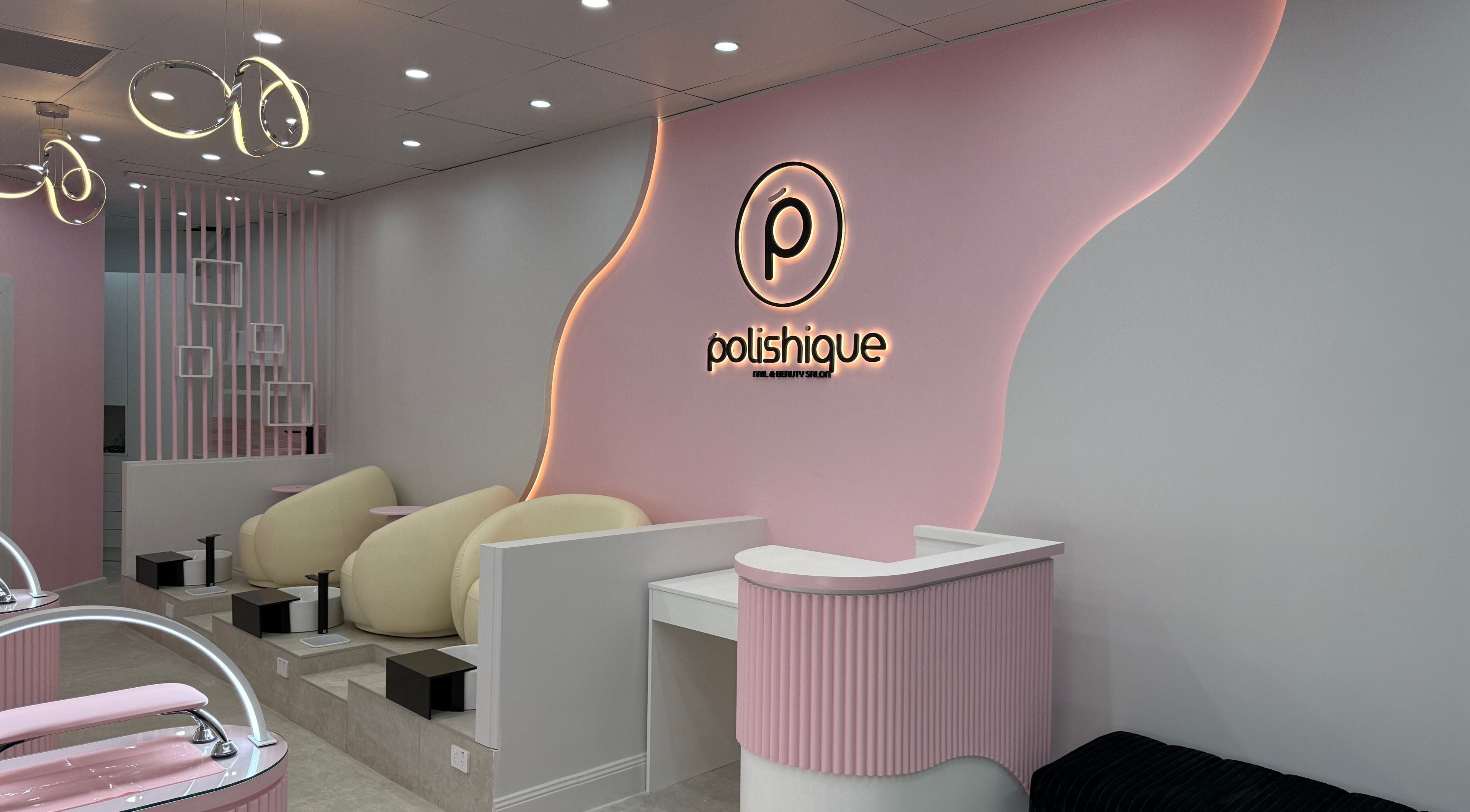 Elegant interior of Polishique, Peakhurst, NSW, AU featuring modern seating and soft pink lighting.