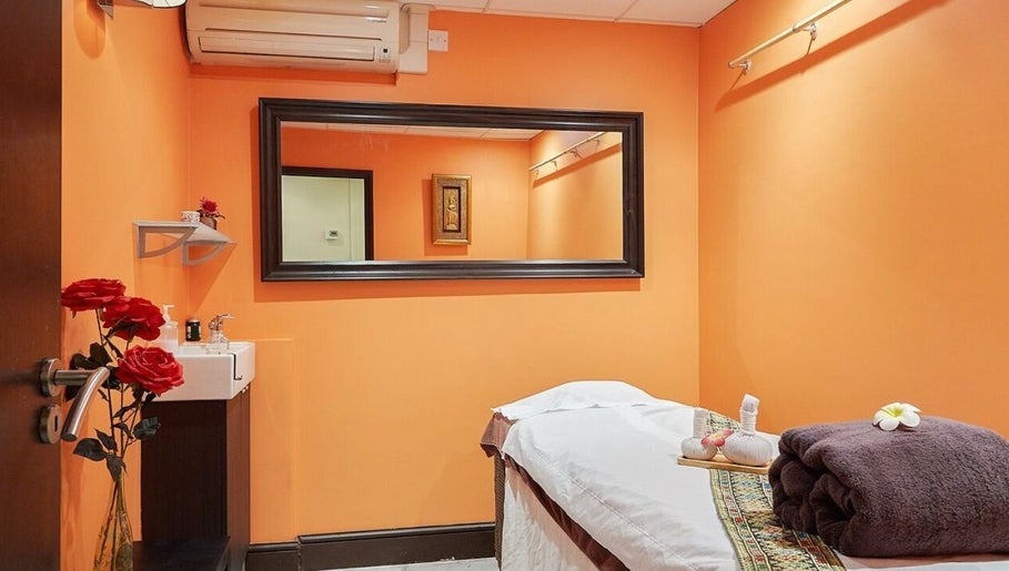 Relaxing therapy room at Eleven Thai Therapy in London, England, GB, featuring warm orange walls and soothing decor.