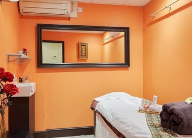 Relaxing therapy room at Eleven Thai Therapy in London, England, GB, featuring warm orange walls and soothing decor.