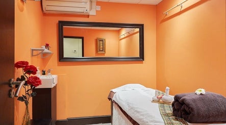 Relaxing therapy room at Eleven Thai Therapy in London, England, GB, featuring warm orange walls and soothing decor.