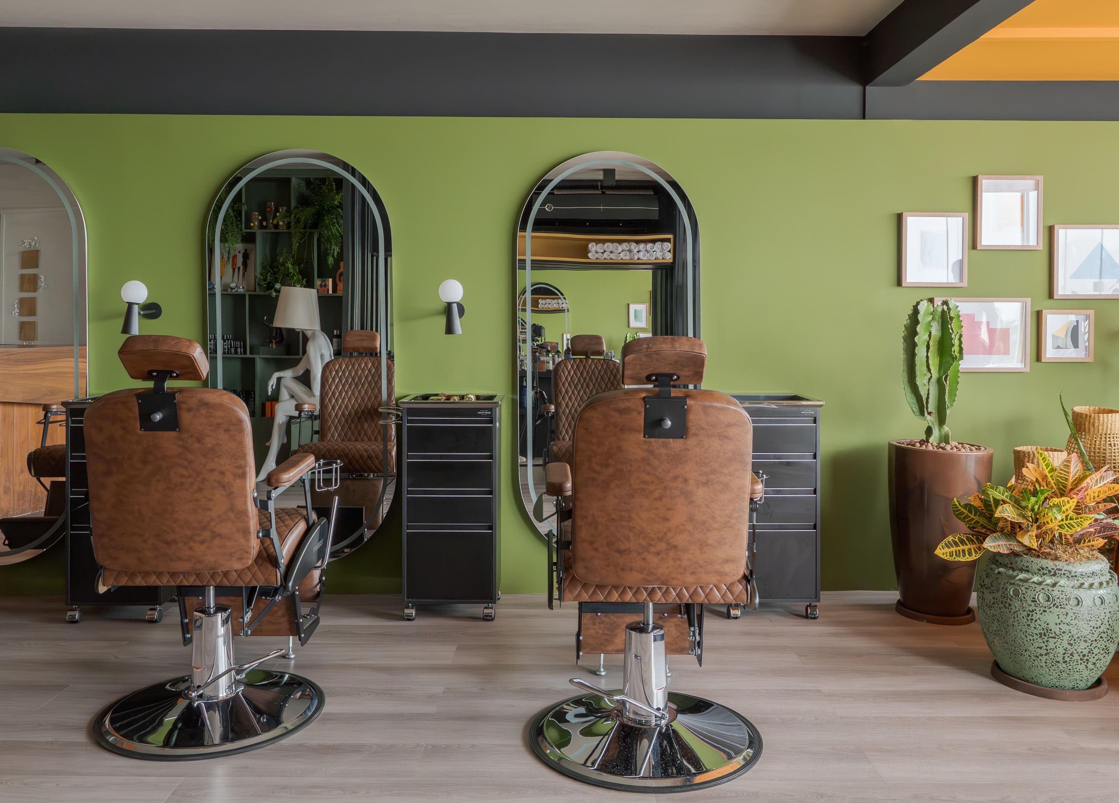 Interior moderno da Carol Scavello Barbearia em Bahia, Bahia, BR, com cadeiras de couro e decoração verde.