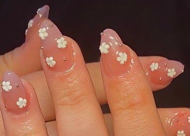 Floral nail art at The Beauty Bar, Drumoak, Scotland, GB showcasing delicate white flowers on a pink base.