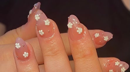 Floral nail art at The Beauty Bar, Drumoak, Scotland, GB showcasing delicate white flowers on a pink base.