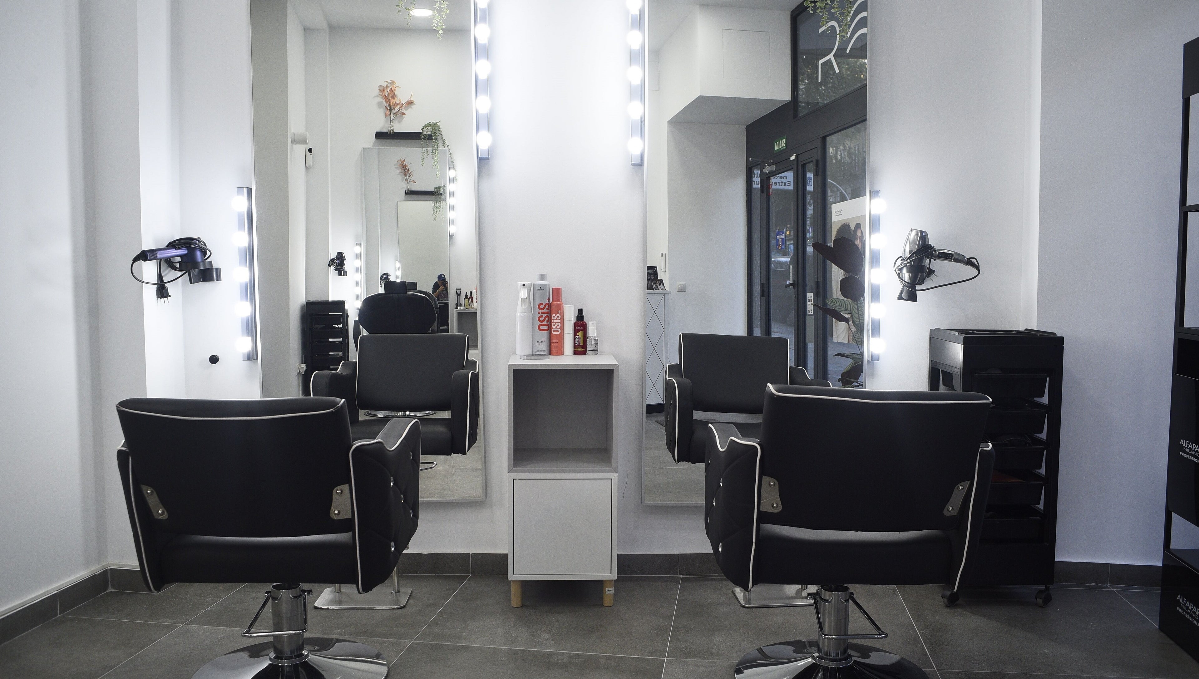 Interior de peluquería en Revive, Madrid, Comunidad De Madrid, ES, con elegantes sillas y espejos iluminados.