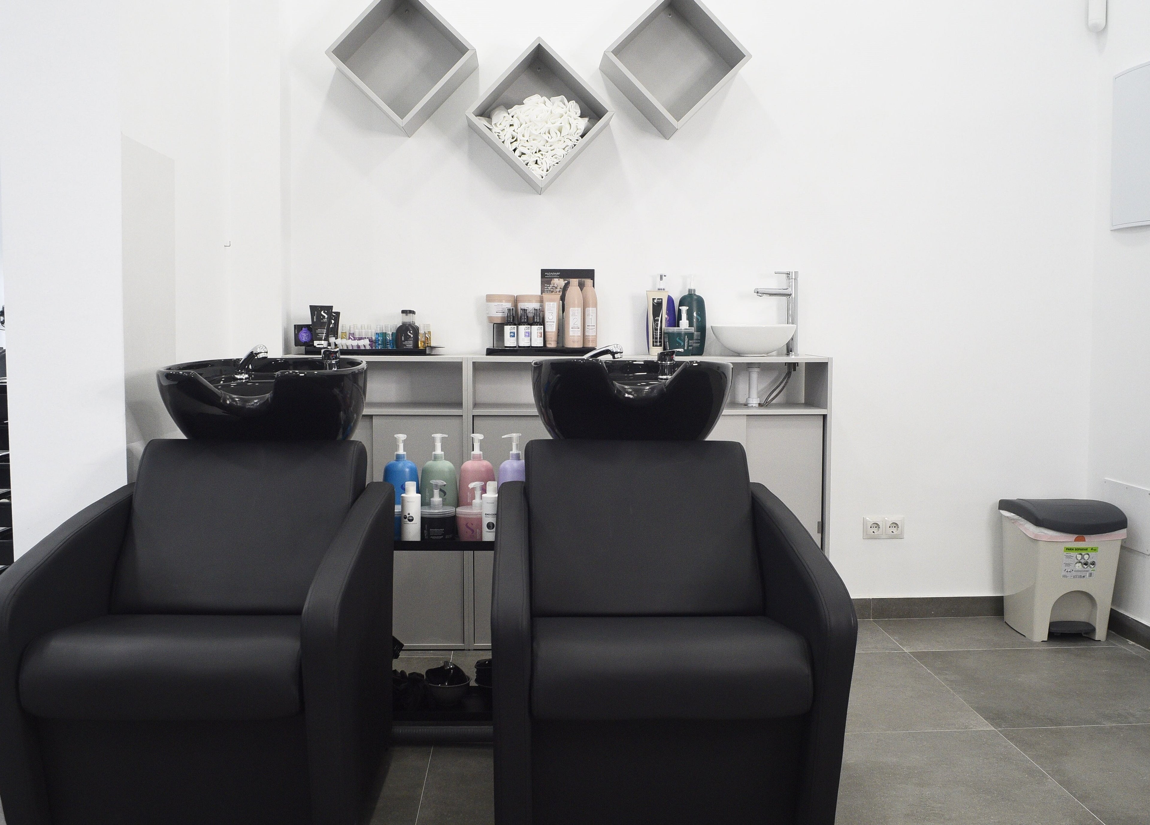 Área de lavado en Revive, Madrid, Comunidad De Madrid, ES, con sillas negras y productos de belleza.