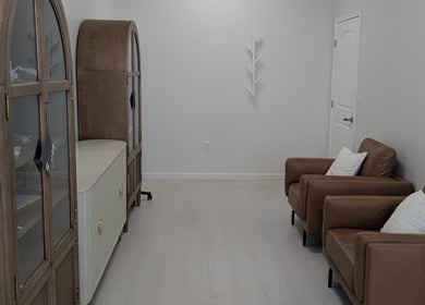 Chic seating area at Identity Aesthetics, Katy, Texas with leather chairs and cabinets.