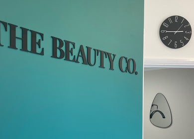 Teal wall with 'The Beauty Co.' sign and black clock, Rugby, England, GB.