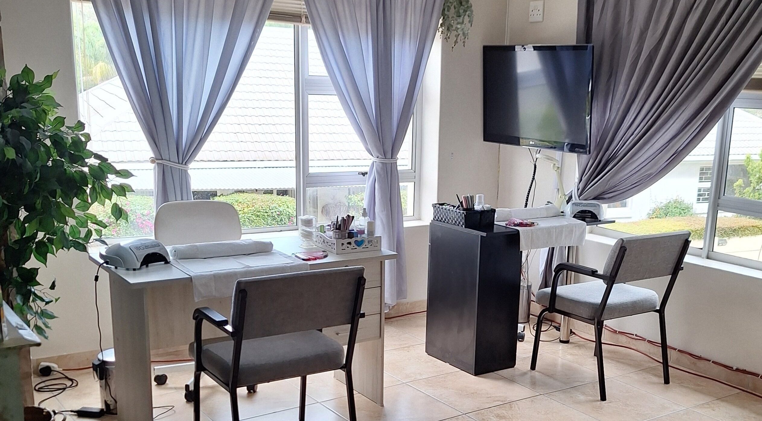 Bright interior of Arukah Skin & Beauty, Paarl, Western Cape, ZA, featuring a manicure station by large windows.