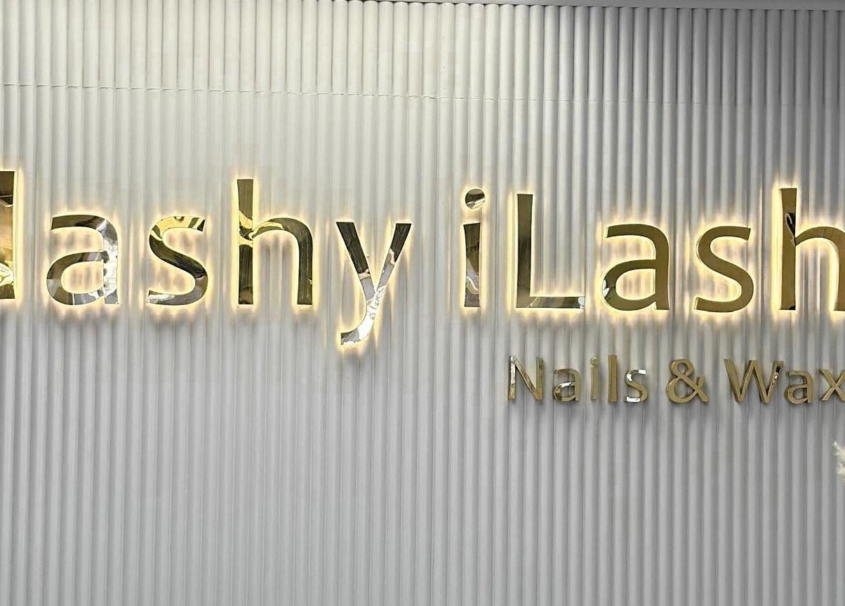 Illuminated Flashy iLash sign in Auckland, Auckland, NZ on a textured wall with decorative flowers.