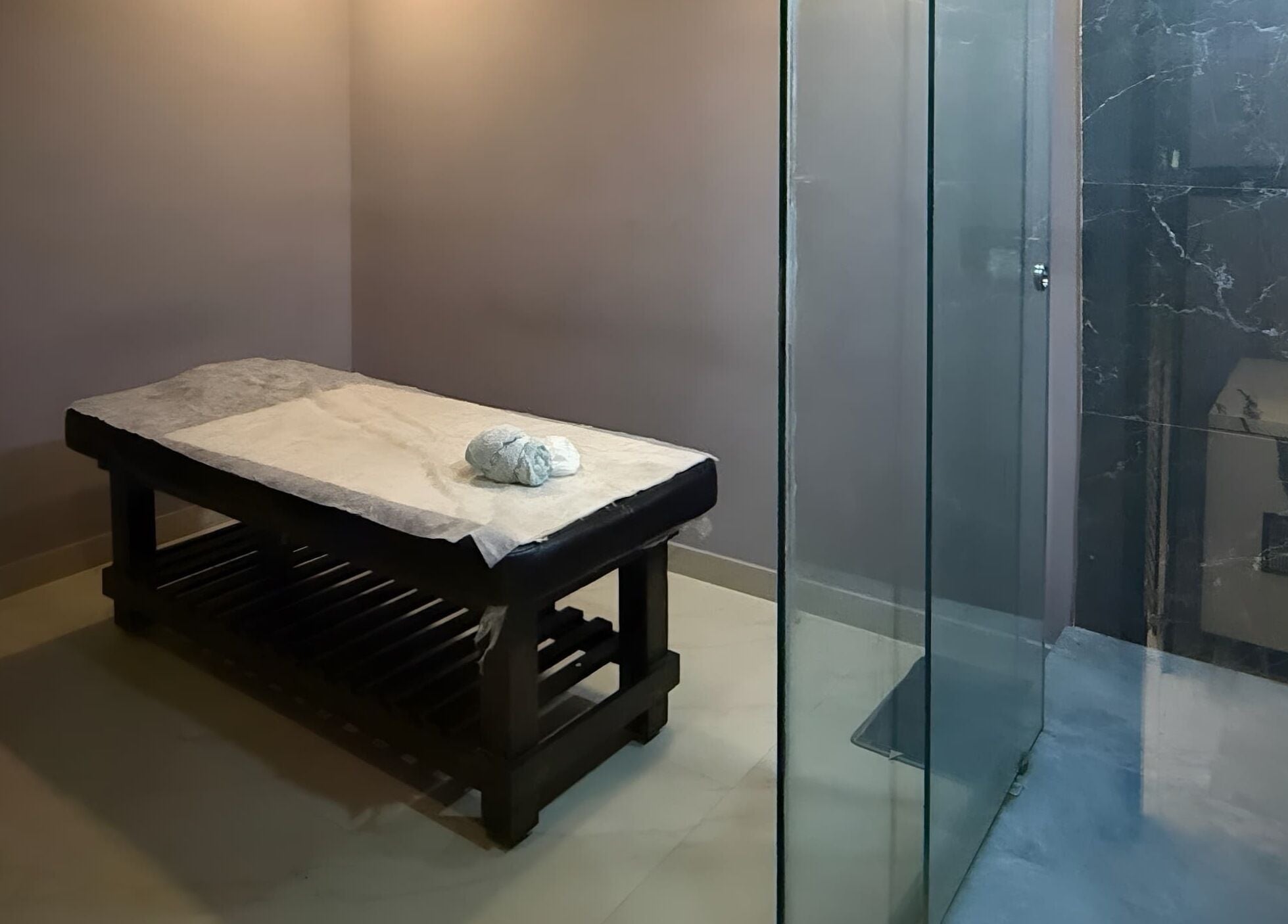 Luxury treatment room at Ajna Spa, Bengaluru, Karnataka, IN. Featuring a massage table and glass shower.