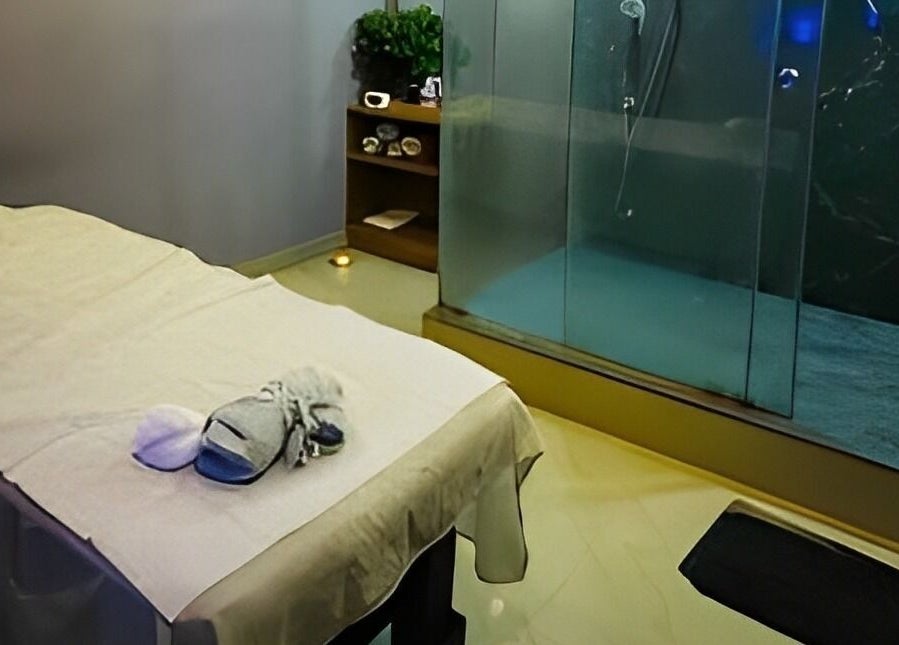 Calm treatment room at Ajna Spa in Bengaluru, Karnataka, IN with massage table and glass shower.