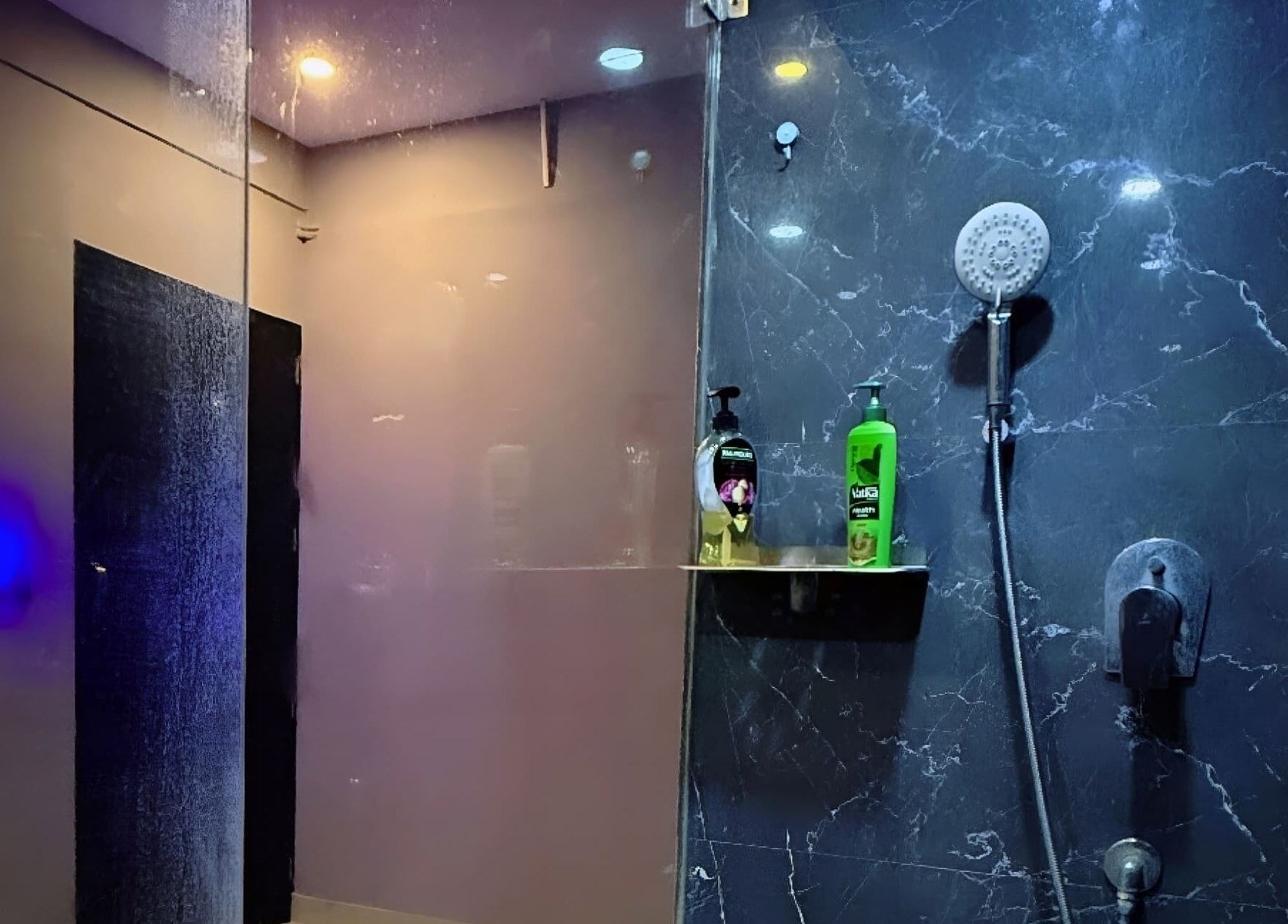 Luxurious black marble shower at Ajna Spa, Bengaluru, Karnataka, IN, featuring premium bath products.