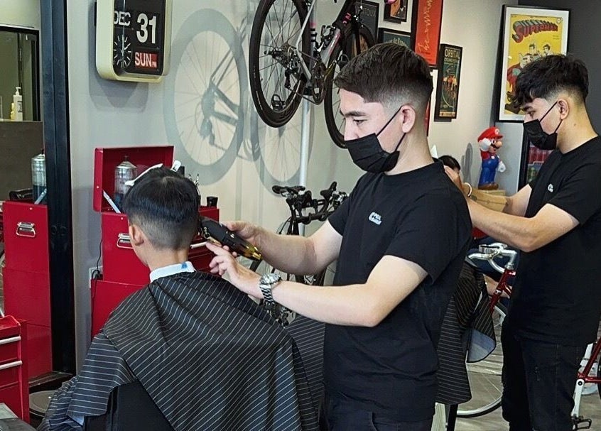 Barbers providing haircuts at Pedal Barbers in Shah Alam, Selangor, MY, with bicycles as decor.