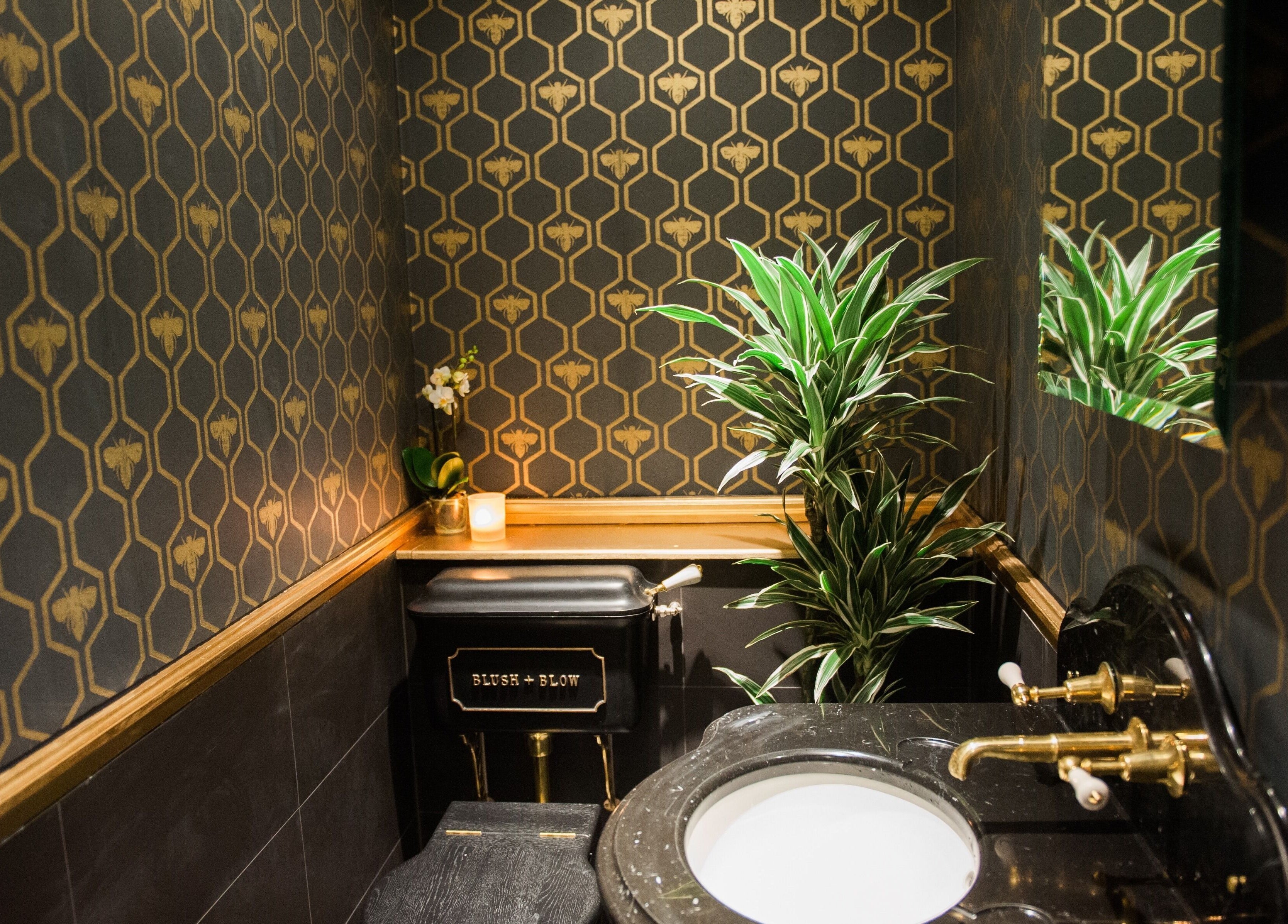 Elegant bathroom at Blush + Blow London, featuring bee-patterned walls and lush greenery in London, England, GB.