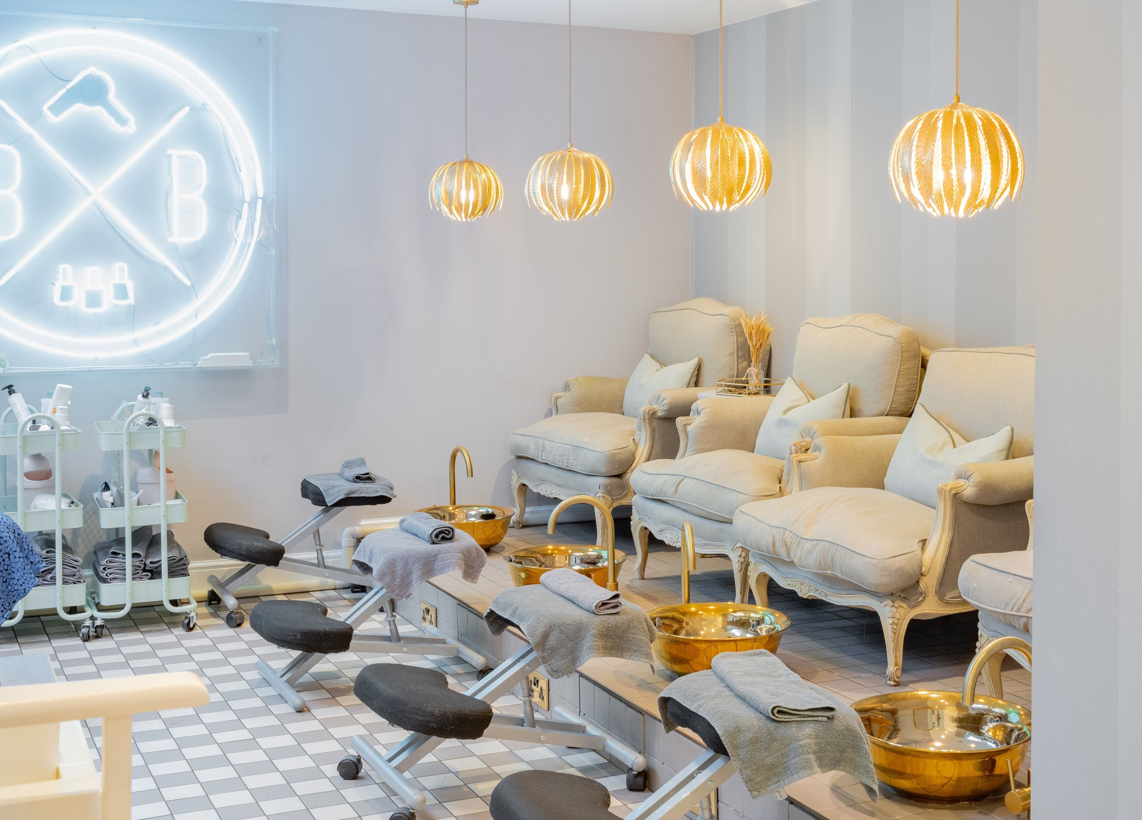 Relaxing pedicure lounge at Blush + Blow London, London, England, GB with plush chairs and gold basins.