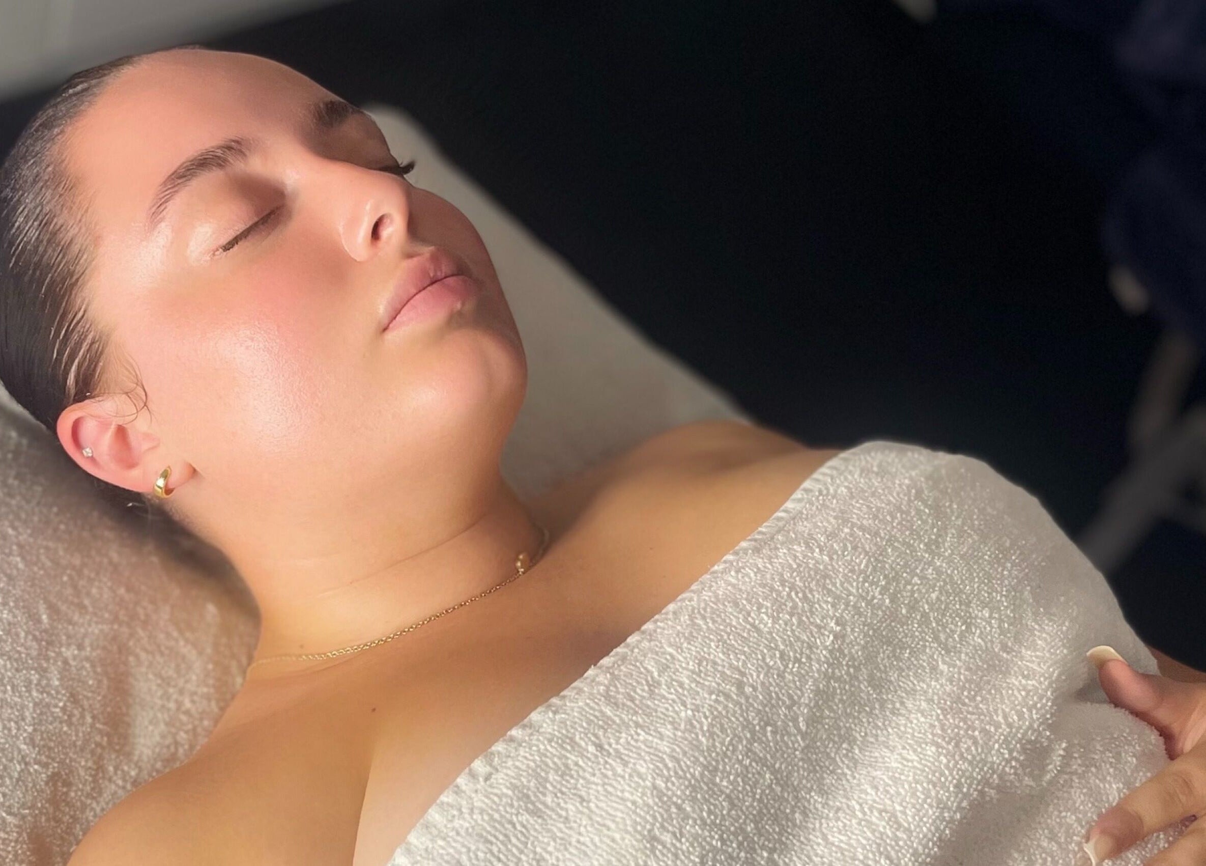 Relaxing spa treatment at The Secret Garden Spa, Weymouth, England, GB. Woman wrapped in a towel, eyes closed.