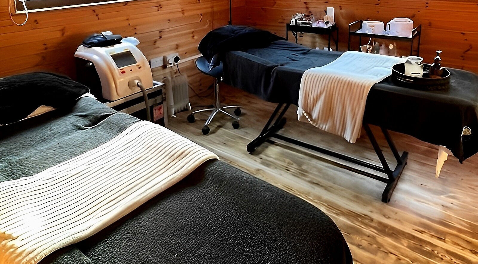 Cozy treatment room at Meraki Birchington, Birchington-on-sea, England featuring massage tables and equipment.