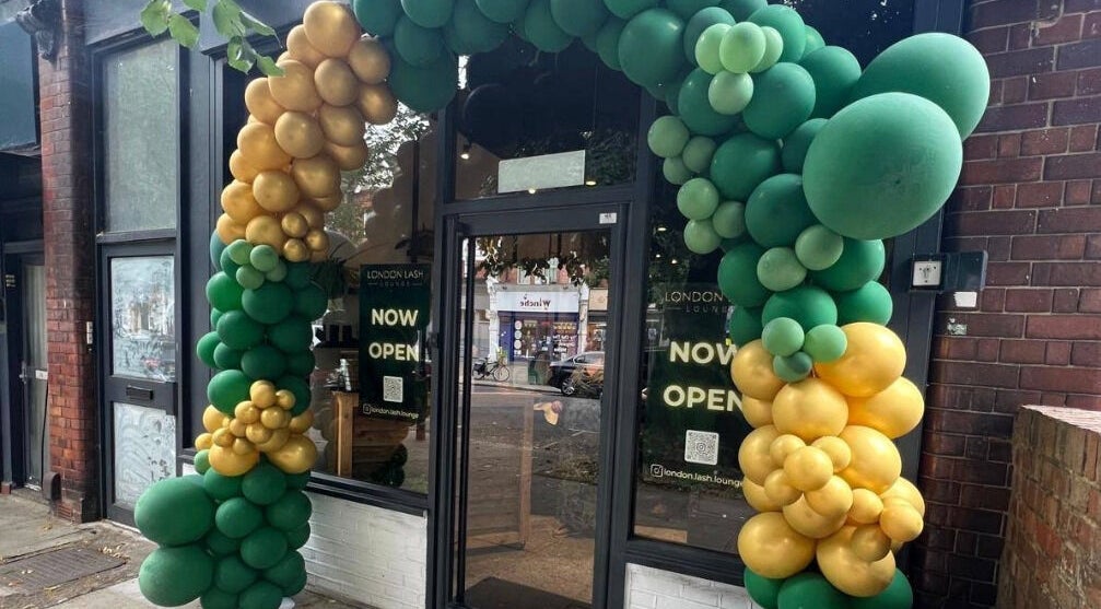 Entrance of London Lash Lounge Ealing, London, England, GB, adorned with green and gold balloons, now open.