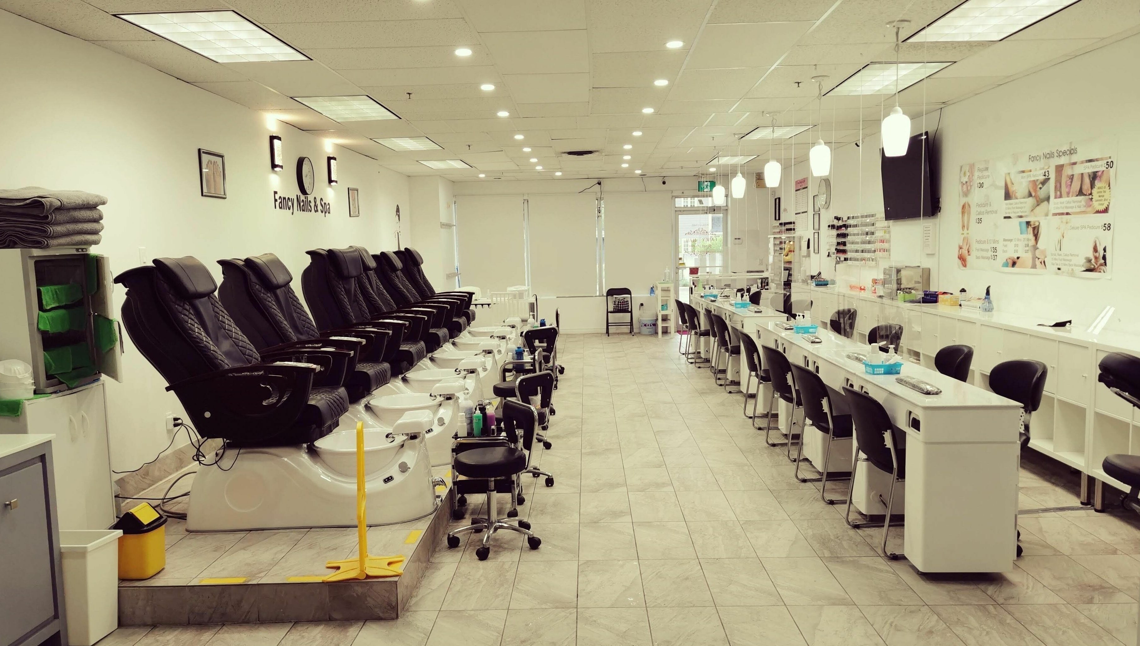 Relaxing interior of Fancy Nails & Spa in Cobourg, Ontario, CA with pedicure chairs and nail stations.