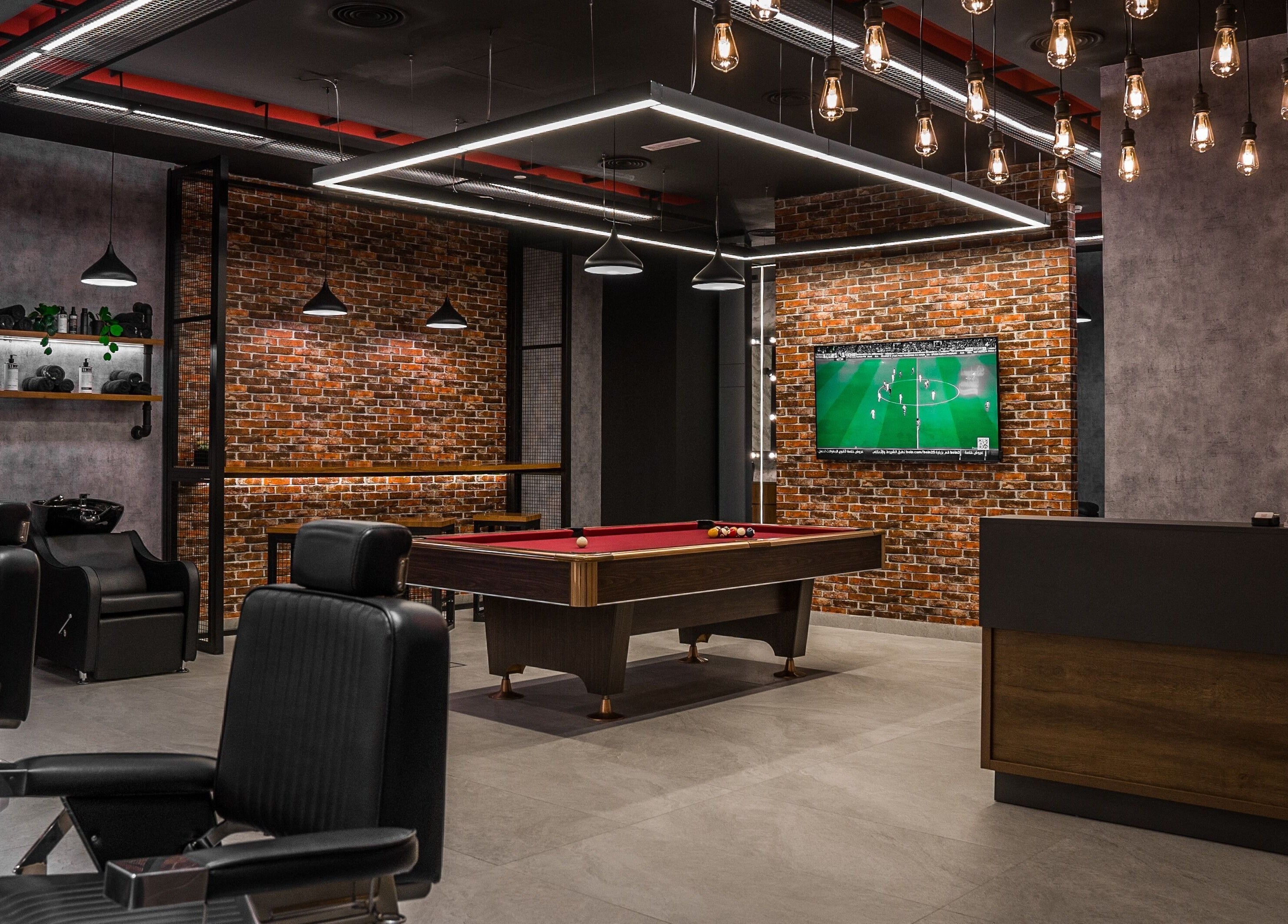 Modern barber shop interior at Backyard Barbers, أبو ظبي, with pool table and stylish seating.
