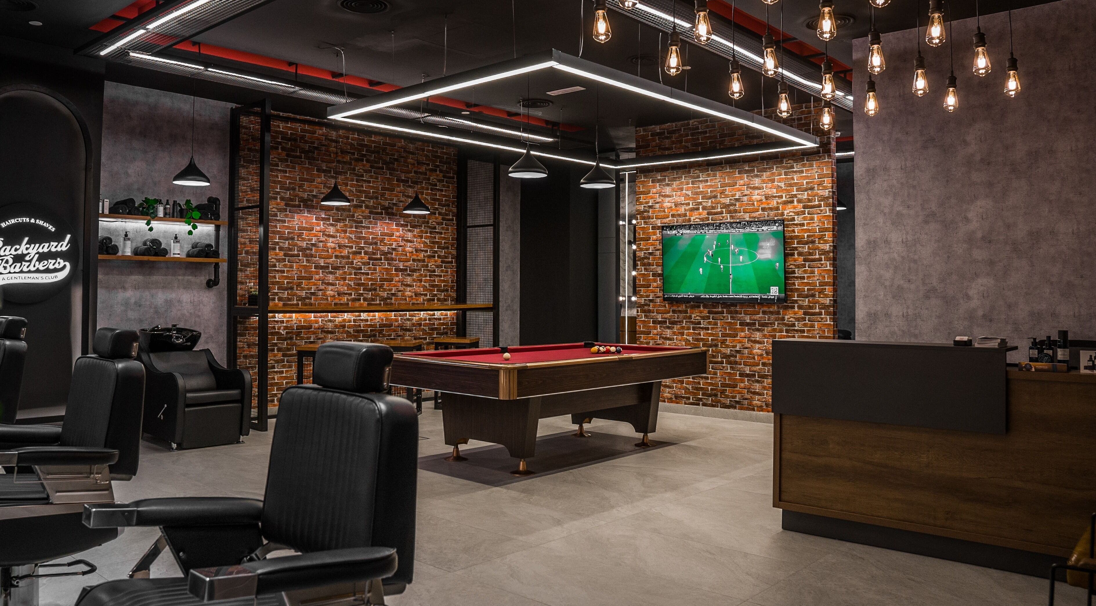 Modern barber shop interior at Backyard Barbers, أبو ظبي, with pool table and stylish seating.